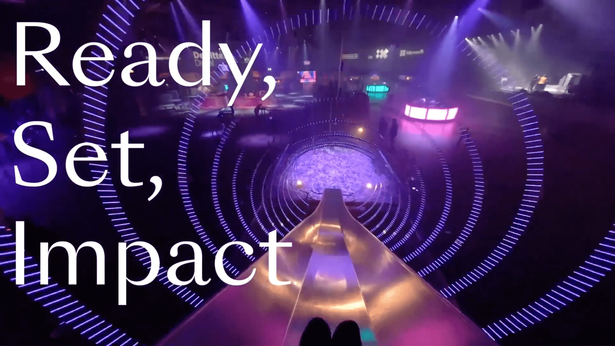 View from the top of an illuminated slide in a dark, futuristic room with purple lighting; people and glowing circular patterns are visible below. Large white text reads: Ready, Set, Impact.
