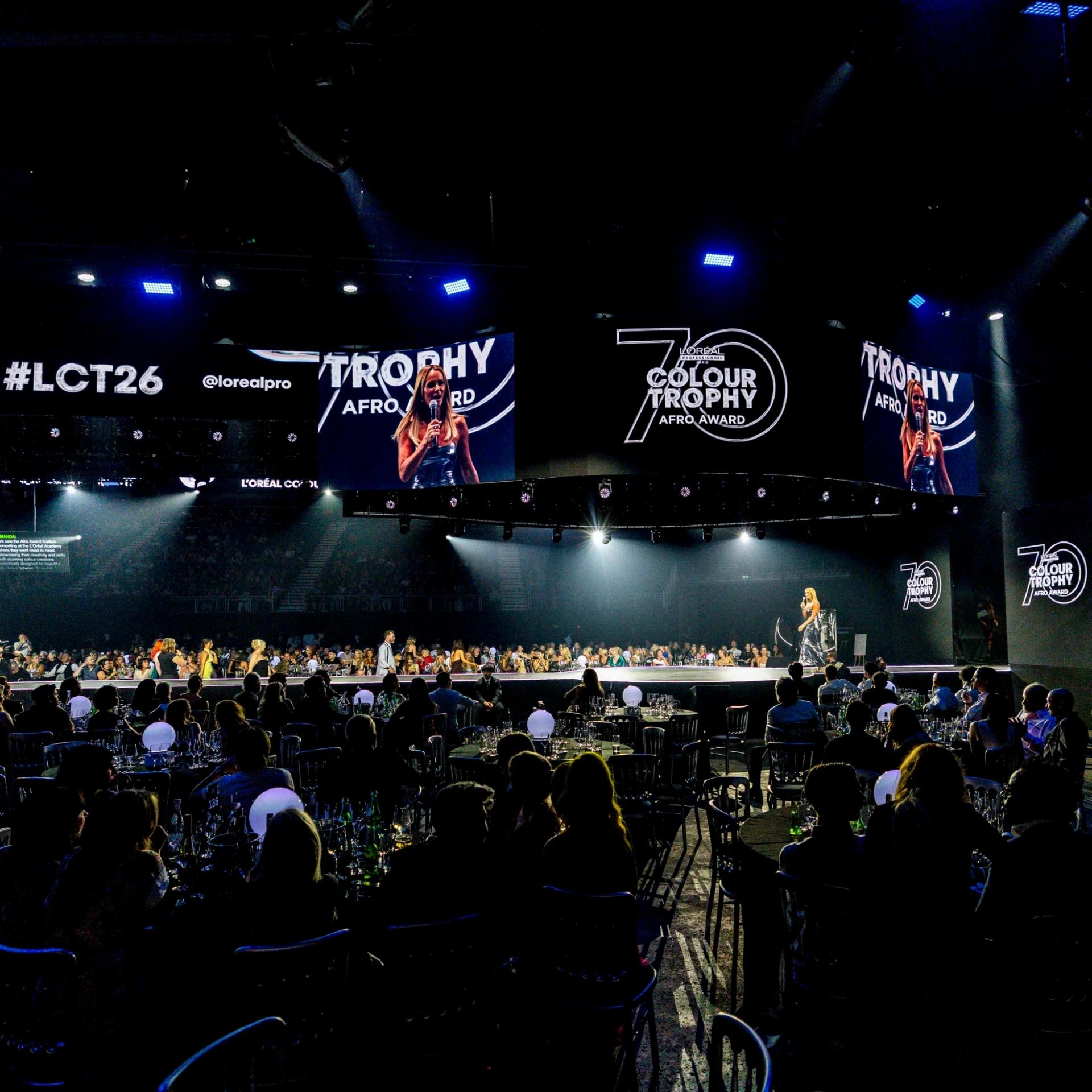 L'Oréal Colour Trophy event with presenter on an illuminated runway and large overhead screens - Encore Event Technologies