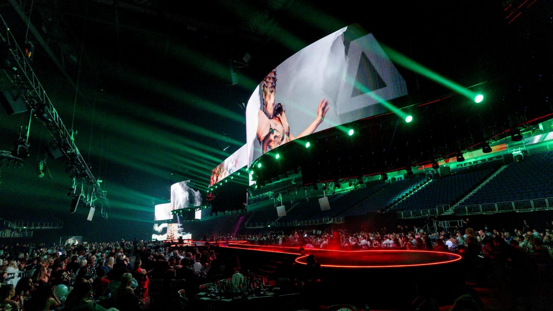 Curved panoramic LED display and red illuminated runway surrounded by arena guests - Encore EMEA